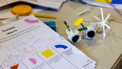 A students plans on paper sit next to a crafted prototype.