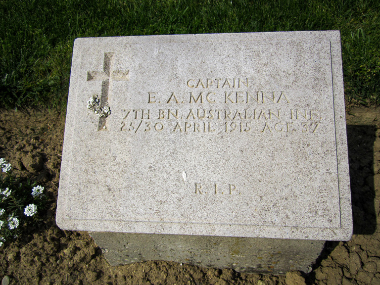 A grave headstone next to small white flowers 