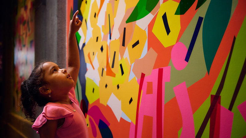 A child points up in wonder at a colourful vignette.