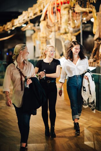 Three friends walking through Dinosaur Walk exhibition during child-free Nocturnal, Melbourne Museum.