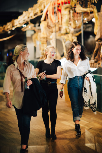 Three friends walking through Dinosaur Walk exhibition during child-free Nocturnal, Melbourne Museum.