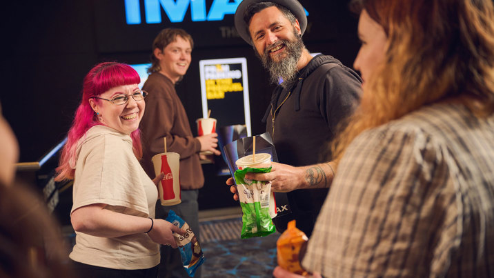 Adults grabbing choctops, popcorn and snacks from the candy bar before seeing a private IMAX screening during Adult Museum Sleepovers at Melbourne Museum.