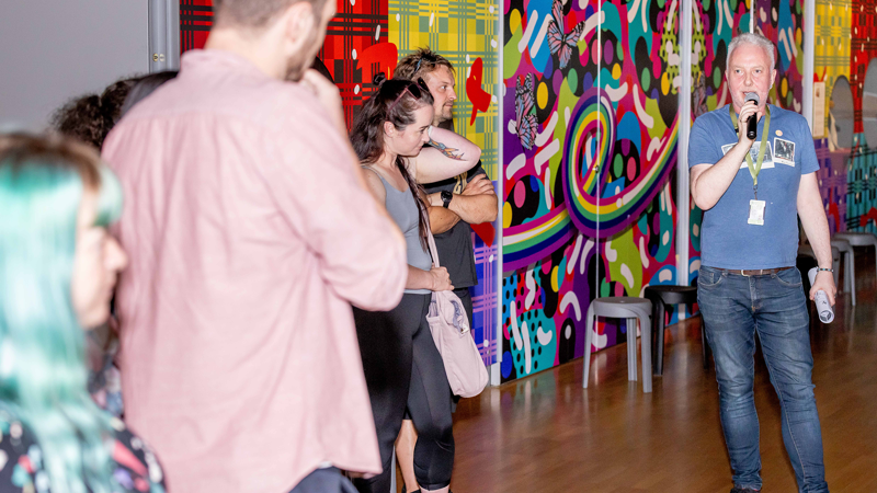 A tour guide leads a group of museum goers through an exhibition