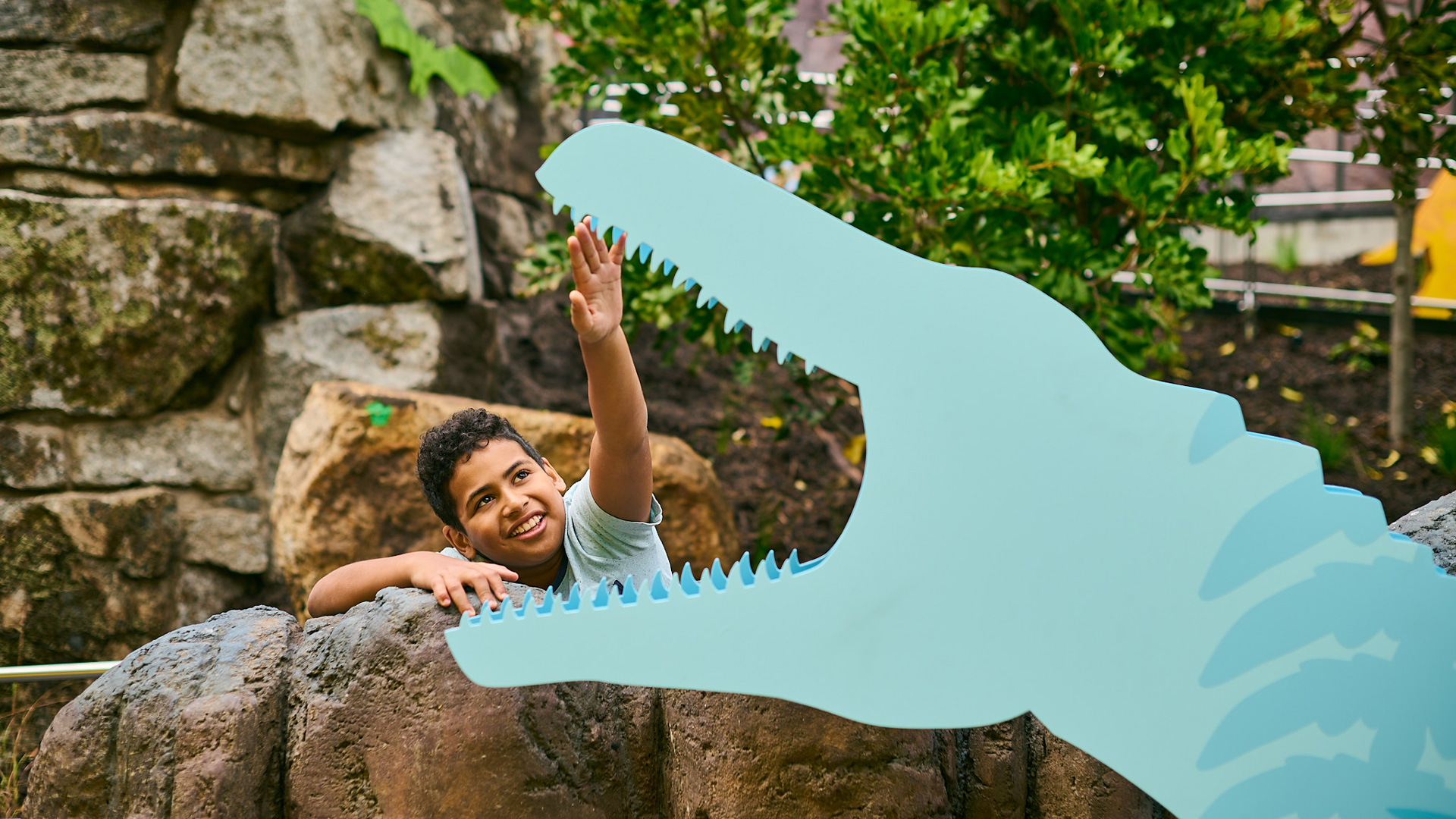 A boy looking into the jaws of a dinosaur figure