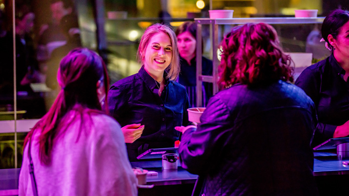 A woman smiles as she hands a order of food to museum goers.