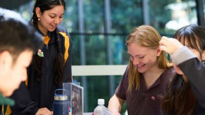 A student facilitator runs an activity with three other students who are folding origami together. 