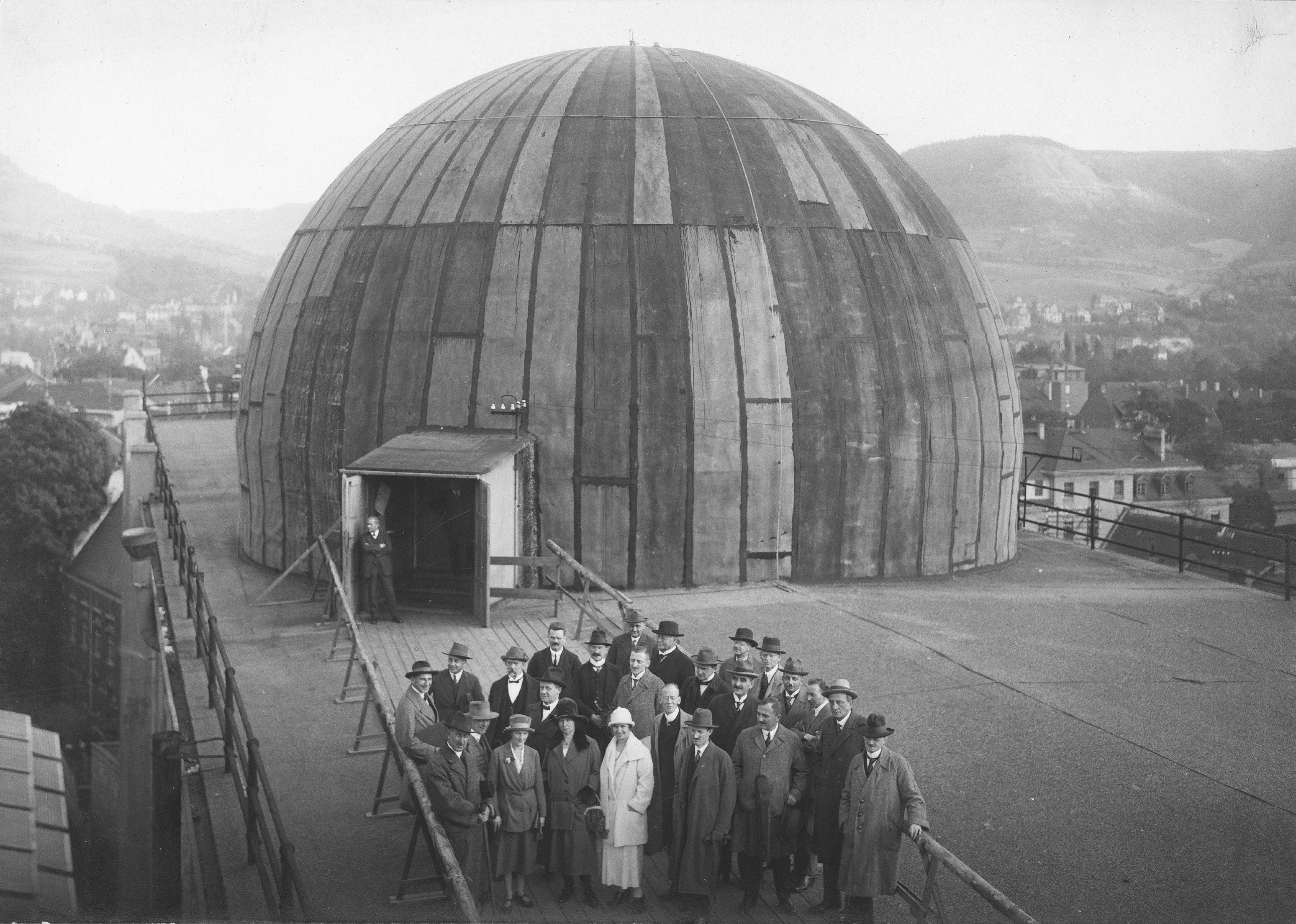 A large group of well-dressed people pose at the opening of the world’s very first opto-mechanical projection planetarium in 1923.