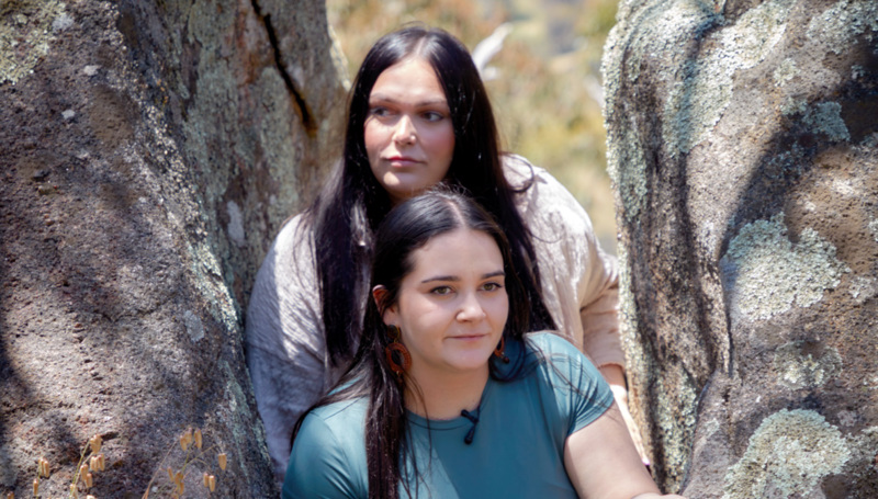 Portrait of two women looking in the distance between two large boulders